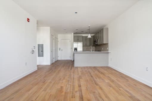a renovated living room and kitchen with white walls and wood floors