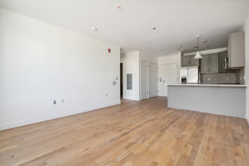 the living room and kitchen of a new home with white walls and wood floors