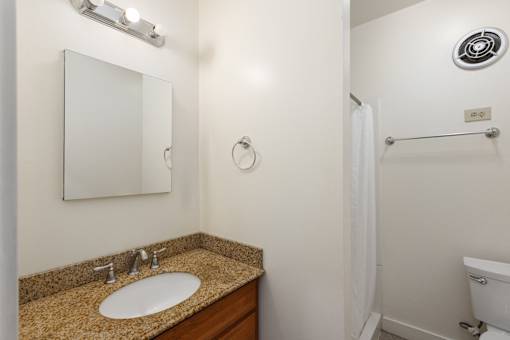 A bathroom with a sink, mirror, and shower at Midtown Apartments, Portland, Oregon
