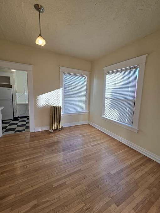 A wooden floor leads up to a window in a room with a white ceiling. at Casa Del Rey Apartments, Apartments, Portland, OR