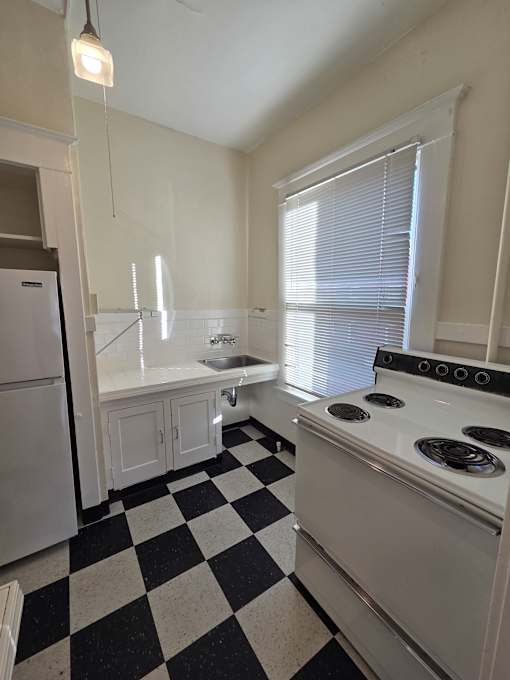A kitchen with a checkered floor and a stove top oven. at Casa Del Rey Apartments, Portland