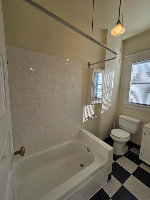 A bathroom with a skylight and a black and white checkered floor. at Casa Del Rey Apartments, Portland, Oregon