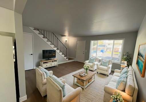 A living room with a staircase and a television.