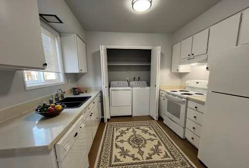 A kitchen with white appliances and cabinets.