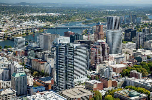 A cityscape with a river and a bridge in the background.