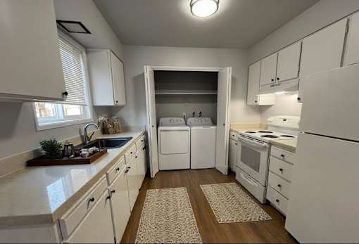 A white kitchen with a sink, stove, and refrigerator.