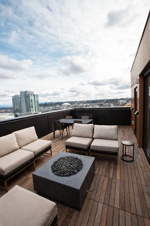 A balcony with a table and chairs overlooking a cityscape.