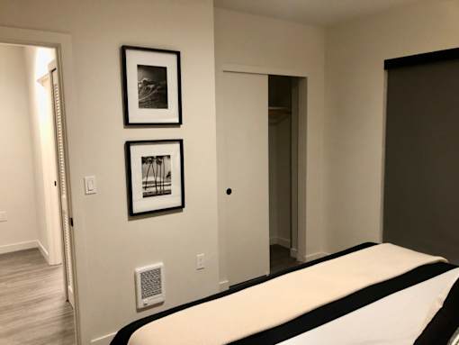 A bedroom with a bed, two pictures on the wall, and a door.