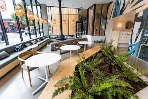 A modern cafe with wooden tables and chairs and a green plant in the middle at Brookland Apartments, Portland, OR 97202