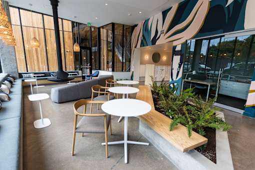 a seating area with tables and chairs in a hotel lobby at Brookland Apartments, Portland, 97202