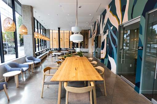 A long wooden table is surrounded by chairs in a room with a wall mural at Brookland Apartments, Portland