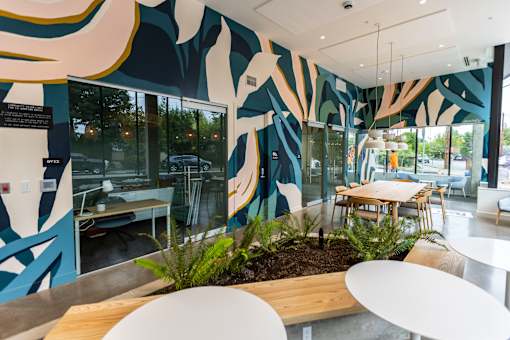 a communal area with tables and chairs and a large mural on the wall at Brookland Apartments, Portland, Oregon