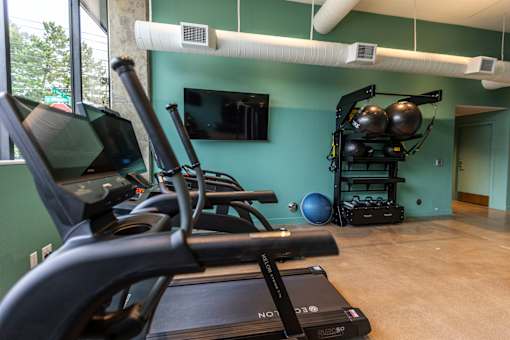 a gym with cardio equipment and a tv in the corner at Brookland Apartments, Portland, OR