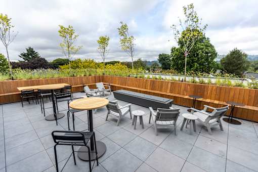 a rooftop patio with tables and chairs and a pool at Brookland Apartments, Portland, OR 97202