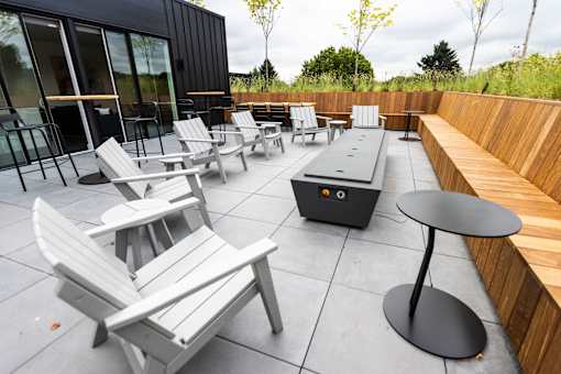 a patio with chairs and tables and a fire pit at Brookland Apartments, Portland