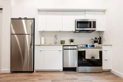 a white kitchen with stainless steel appliances and a stainless steel refrigerator at Brookland Apartments, Oregon