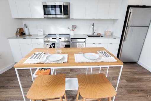 a kitchen with white cabinets and a wooden table with two chairs at Brookland Apartments, Portland, 97202