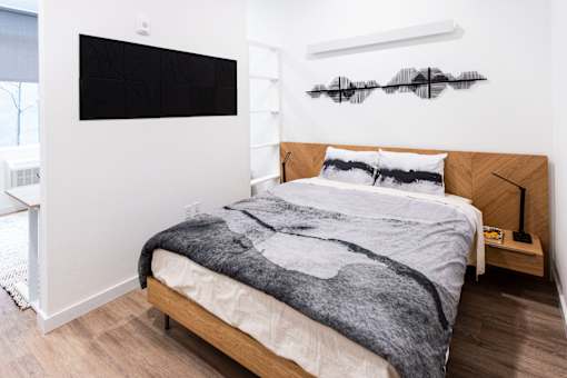 a bedroom with white walls and a bed with a gray blanket at Brookland Apartments, Oregon 97202