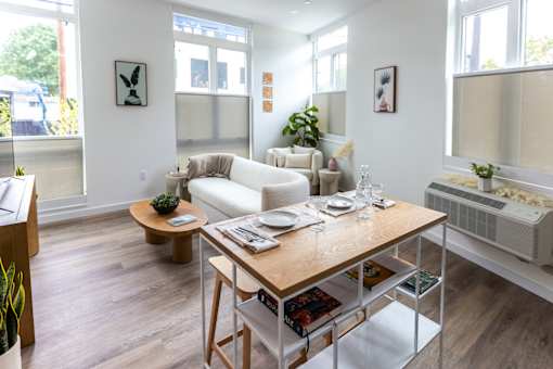 a living room and dining room with a wooden table and white furniture at Brookland Apartments, Portland, OR 97202