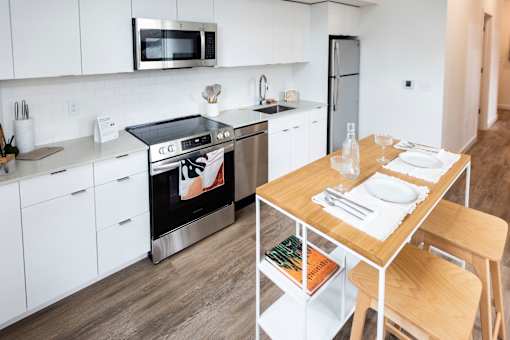 a kitchen with white cabinets and a wooden table at Brookland Apartments, Portland, OR
