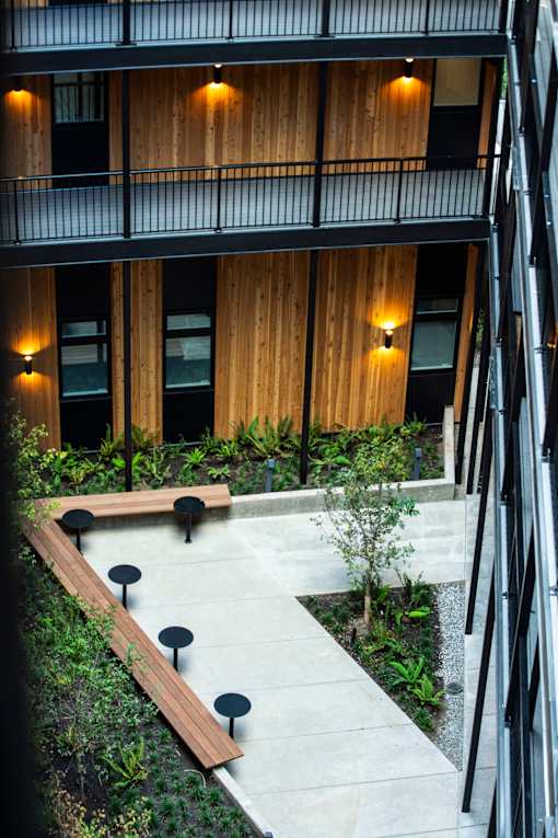 a courtyard with benches and plants in front of a building at Brookland Apartments, Portland, Oregon