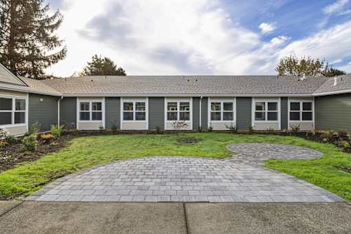 A house with a grey roof and a grey brick walkway in front.