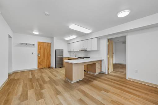 A kitchen with a wooden floor and white walls.