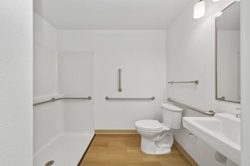 A white toilet sits in a small bathroom next to a bathtub.