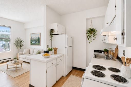 A white kitchen with a stove top oven and a fridge.
