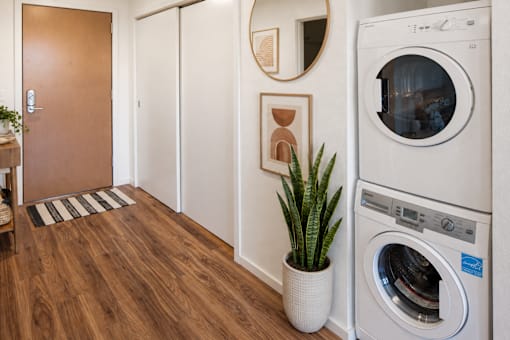 A washing machine is placed in a room with wooden flooring.