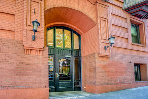 A red brick building with a black door and two lamps on either side at Clay & Tiffany, Portland, 97201