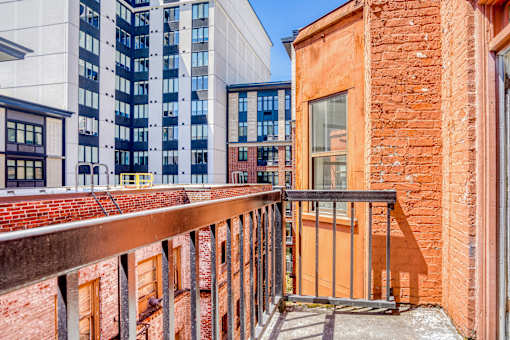 A balcony with a metal railing overlooks a brick building at Clay & Tiffany, Portland, 97201