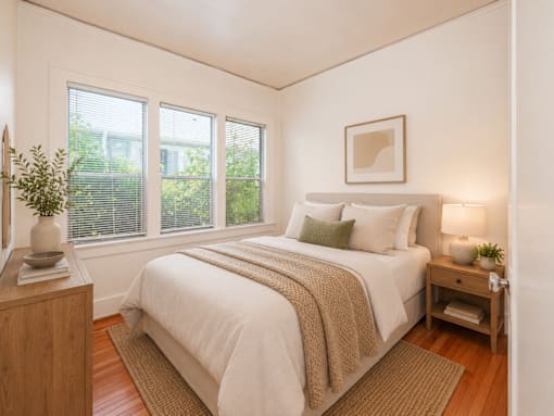 A bedroom with a bed, nightstand, and window.