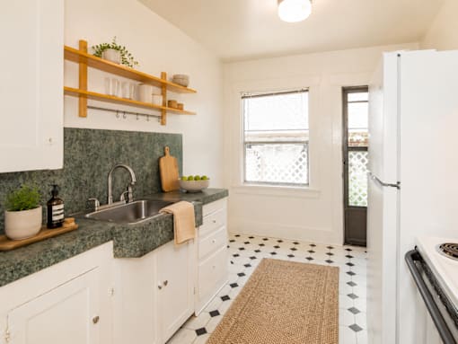 A kitchen with white cabinets and a green counter top.
