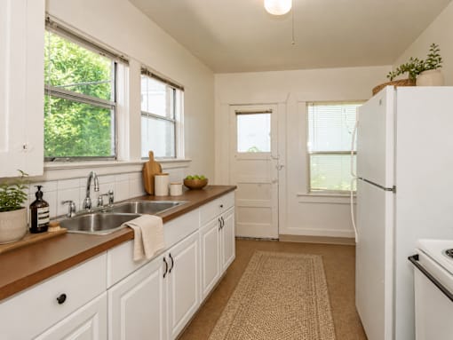 A kitchen with white cabinets and a white fridge.