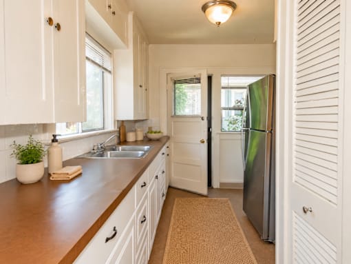 A kitchen with white cabinets and a brown countertop.