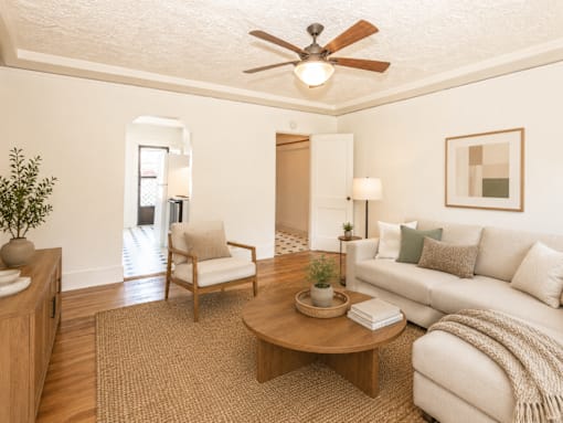 A living room with a white couch, a wooden coffee table, and a ceiling fan.