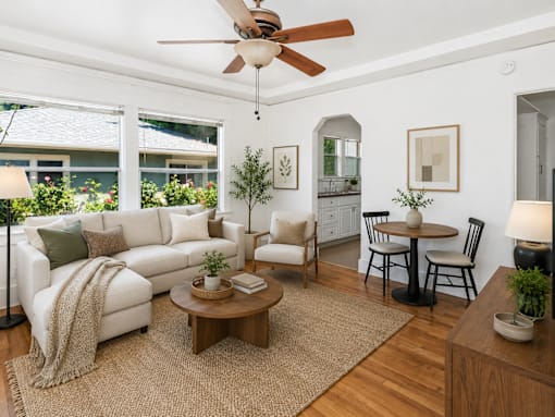 A living room with a white couch, a wooden coffee table, and a ceiling fan.