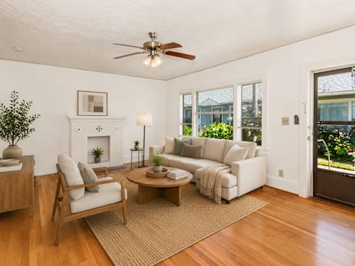 A living room with a fireplace, a sofa, a chair, a coffee table, and a potted plant.
