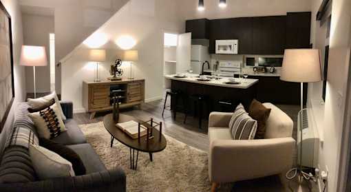 A modern living room with a kitchen area in the background.