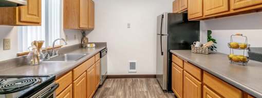 A kitchen with wooden cabinets and a black refrigerator.at Alder Creek Apartments, Vancouver Washington