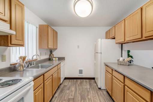 A kitchen with wooden cabinets and a white refrigerator.at Alder Creek Apartments, Vancouver, WA 98682