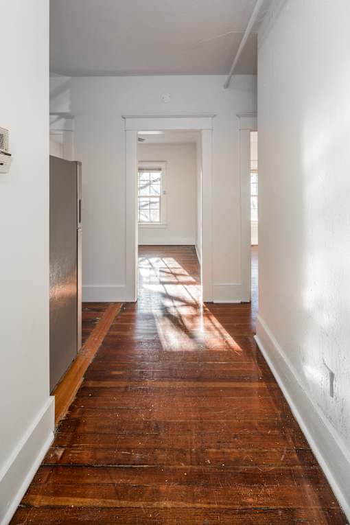 A long hallway with a wooden floor and white walls at Midtown  Apartments, Portland, OR