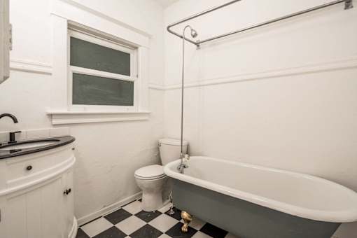A white bathroom with a black and white checkered floor at Midtown Apartments, Oregon, 97209