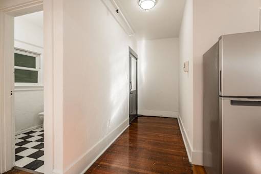 A long hallway with a checkered floor and a refrigerator on the right at Midtown  Apartments, Portland, OR