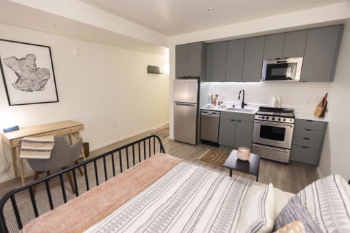 a bedroom with a bed and a kitchen with stainless steel appliances at Moraine, Tacoma, WA