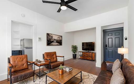 A living room with a brown leather chair and a brown leather couch.