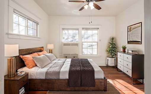 A bedroom with a bed, nightstand, and a ceiling fan.