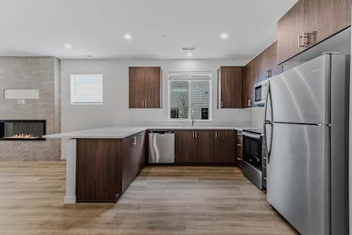 Modern kitchen with a stainless steel refrigerator and wooden cabinets at Thrive at Green Mountain, Camas, WA, Washington