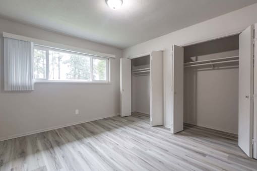 an empty bedroom with a large window and a closet